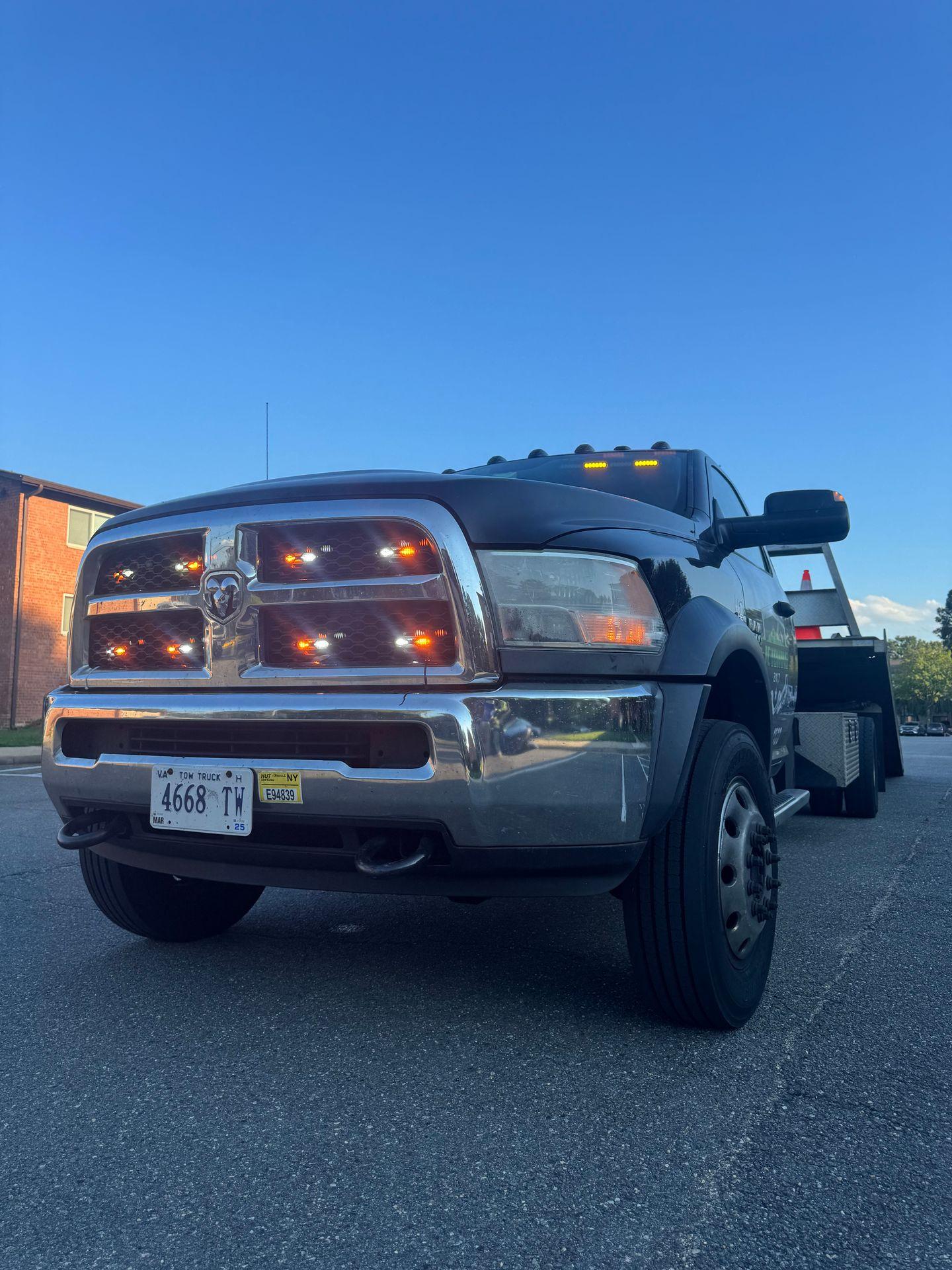 Low-angle view of a large black truck with orange lights under a clear blue sky.