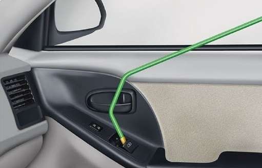 Interior of a car door with a green tool unlocking the door lock mechanism.