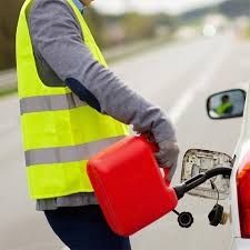 Person in high-visibility vest refueling a car with a red gas can on the roadside.